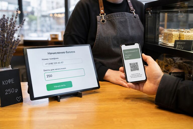 Касса кафе: телефон с виртуальной картой лояльности и QR-кодом, на экране кассы поле телефона и баллы